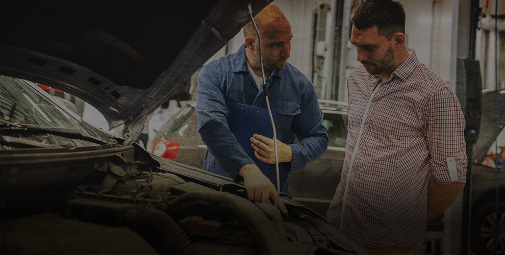 mechanic showing customer something under the bonnet of a car