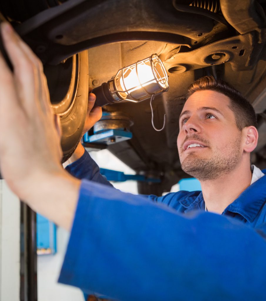 Mechanic using torch to look under car at the repair garage - MOT Testing Bathgate, West Lothian